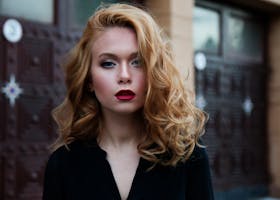 Elegant portrait of a woman in a black top with striking red lips and flowing blond hair.