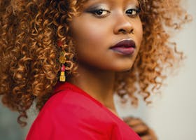 Striking portrait of a woman with curly hair, wearing a red jacket.